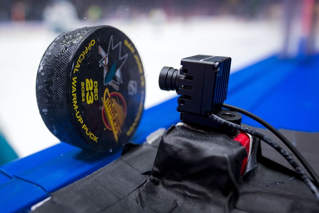 Dec 23, 2024; Vancouver, British Columbia, CAN; A puck blocks a remote broadcast tv camera prior to game between the San Jose Sharks and Vancouver Canucks during warm up prior to a game against the Vancouver Canucks at Rogers Arena. Mandatory Credit: Bob Frid-Imagn Images