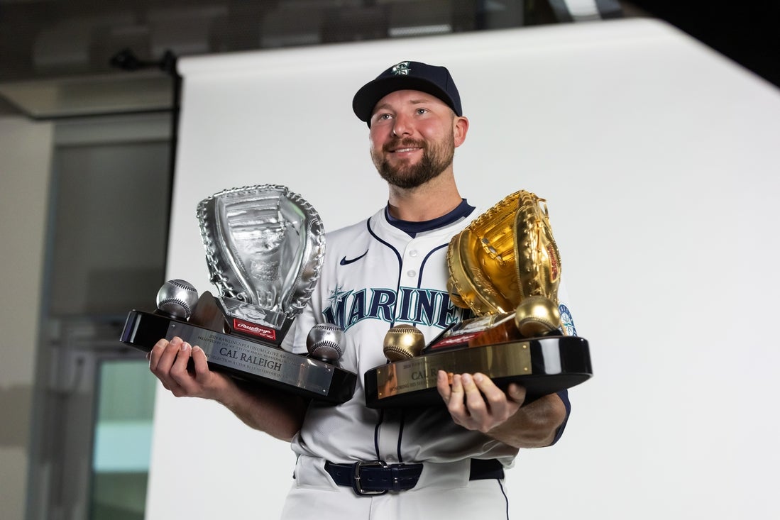 Feb 20, 2025; Peoria, AZ, USA; Seattle Mariners catcher Cal Raleigh poses for a portrait with his Rawlings Gold Glove and Platinum Glove trophies during media day at Peoria Sports Complex. Mandatory Credit: Mark J. Rebilas-Imagn Images