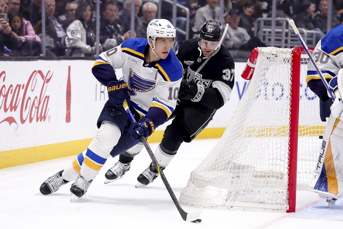 Mar 8, 2025; Los Angeles, California, USA; St. Louis Blues center Brayden Schenn (10) moves the puck ahead of Los Angeles Kings left wing Warren Foegele (37) during the second period at Crypto.com Arena. Mandatory Credit: Ryan Sun-Imagn Images