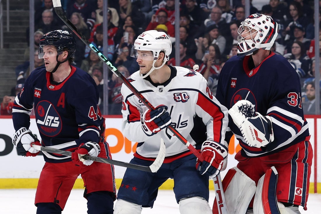 Mar 25, 2025; Winnipeg, Manitoba, CAN; Winnipeg Jets defenseman Josh Morrissey (44), Washington Capitals center Nic Dowd (26) and Winnipeg Jets goaltender Connor Hellebuyck (37) wait for an incoming shot in the first period at Canada Life Centre. Mandatory Credit: James Carey Lauder-Imagn Images
