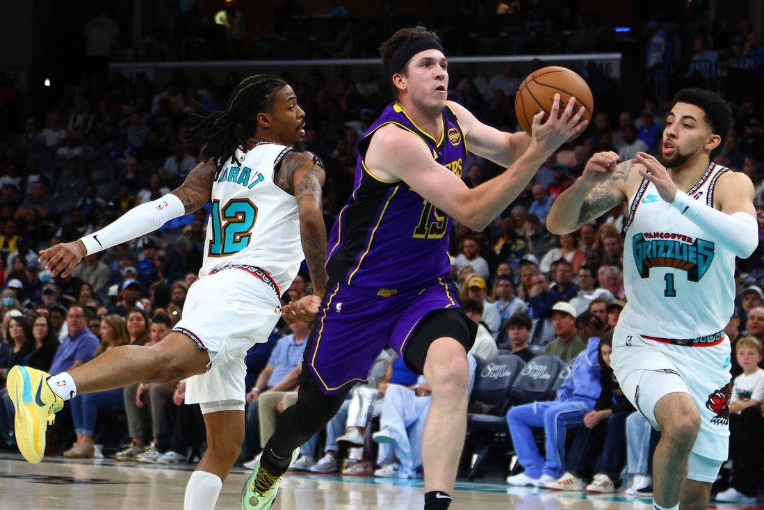Mar 29, 2025; Memphis, Tennessee, USA; Los Angeles Lakers guard Austin Reaves (15) drives to the basket between Memphis Grizzlies guard Ja Morant (12) and Memphis Grizzlies guard Scotty Pippen Jr. (1) during the second quarter at FedExForum. Mandatory Credit: Petre Thomas-Imagn Images