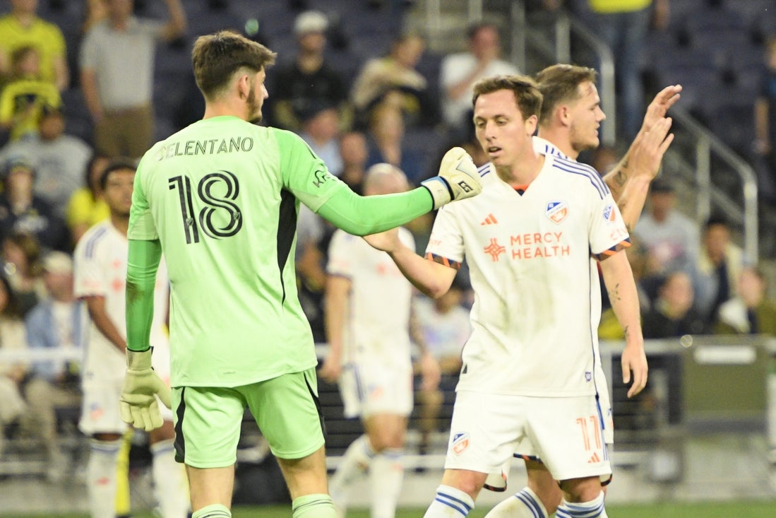 Mar 29, 2025; Nashville, Tennessee, USA; FC Cincinnati forward Corey Baird (11) congratulates goalkeeper Roman Celentano (18) on the win against the Nashville SC during the second half at Geodis Park. Mandatory Credit: Steve Roberts-Imagn Images