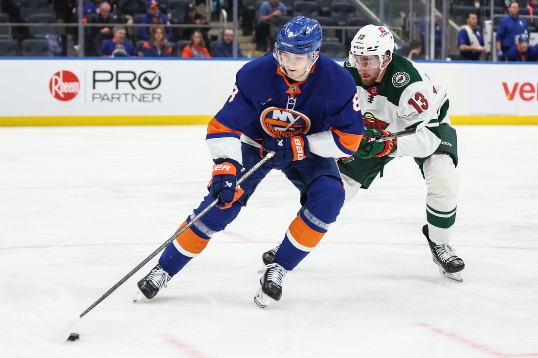 Apr 4, 2025; Elmont, New York, USA; New York Islanders defenseman Noah Dobson (8) and Minnesota Wild center Yakov Trenin (13) battle for control of the puck in the third period at UBS Arena. Mandatory Credit: Wendell Cruz-Imagn Images