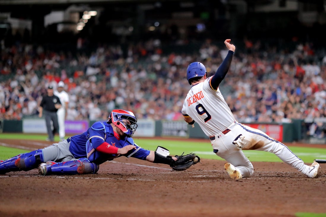 Apr 21, 2025; Houston, Texas, USA; Houston Astros first baseman Zach Dezenzo (9) slides home to score a run while beating the tag from Toronto Blue Jays catcher Alejandro Kirk (30) during the seventh inning at Daikin Park. Mandatory Credit: Erik Williams-Imagn Images