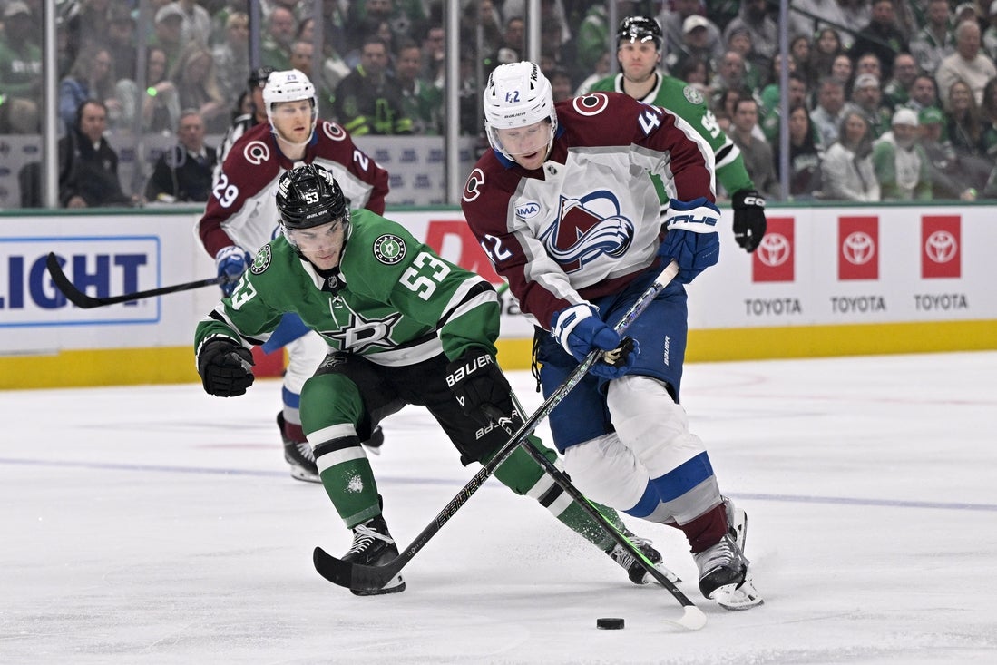 Apr 21, 2025; Dallas, Texas, USA; Colorado Avalanche defenseman Josh Manson (42) skates with the puck past Dallas Stars center Wyatt Johnston (53) during the first period in game two of the first round of the 2025 Stanley Cup Playoffs at American Airlines Center. Mandatory Credit: Jerome Miron-Imagn Images