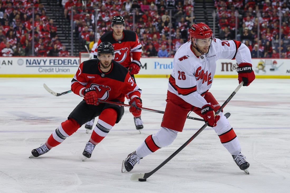 Apr 27, 2025; Newark, New Jersey, USA; Carolina Hurricanes defenseman Sean Walker (26) shoots the puck as New Jersey Devils center Justin Dowling (37) defends during the first period in game four of the first round of the 2025 Stanley Cup Playoffs at Prudential Center. Mandatory Credit: Ed Mulholland-Imagn Images